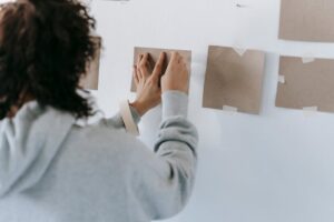 A woman creatively arranging blank cards on the wall to enhance home decor.